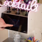 Ein Finger bedient eine Cocktailmaschine