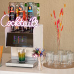 Eine Cocktailmaschine aufgebaut auf einem Tisch mit Gläsern, Strohhalmen und Dekoration